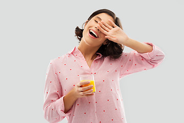 Image showing happy yawning young woman in pajama with juice