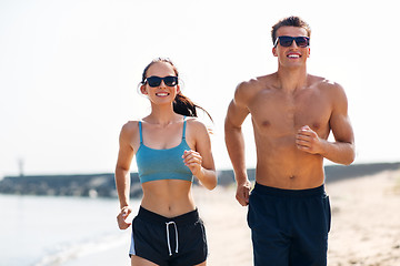 Image showing couple in sports clothes running along on beach