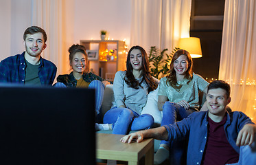 Image showing happy friends watching tv at home in evening