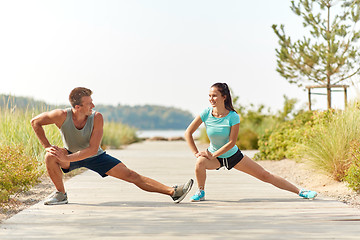 Image showing smiling couple stretching legs on beach