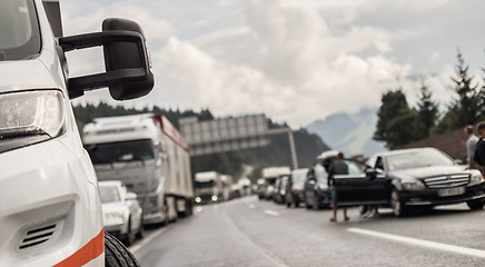 Image showing Typical scene on European highways during summer holiadays rush hour. A traffic jam with rows of cars tue to highway car accident. Empty emergency lane. Shallow depth of field