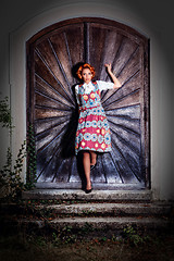 Image showing Portrait of a young woman standing in a dirndl on a wooden wall