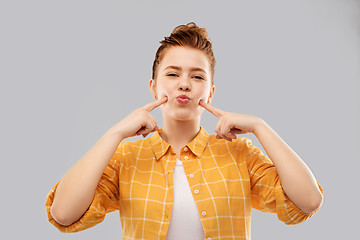 Image showing smiling red haired teenage girl blowing her cheeks