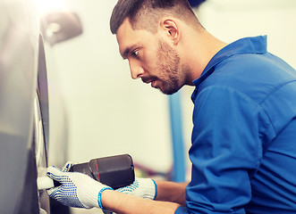 Image showing mechanic with screwdriver changing car tire