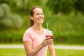 Image showing woman drinking smoothie after exercising in park