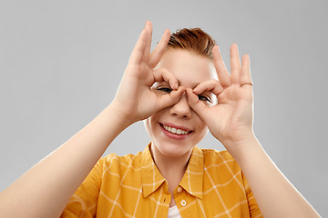 Image showing red haired teenage girl making finger glasses