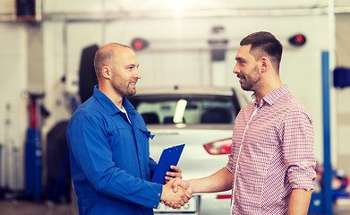 Image showing auto mechanic and man shaking hands at car shop