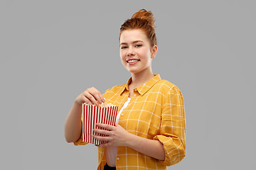 Image showing smiling red haired teenage girl eating popcorn