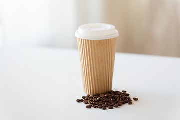 Image showing close up cup and roasted coffee beans on table