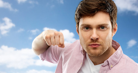 Image showing angry young man ready for fist punch over sky