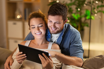 Image showing happy couple using tablet pc at home in evening