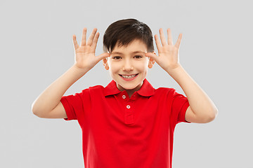 Image showing little boy in red t-shirt making big ears by hands