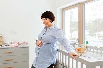 Image showing happy pregnant woman next to baby bed at home