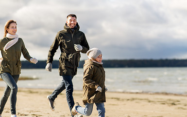 Image showing happy family running along autumn beach