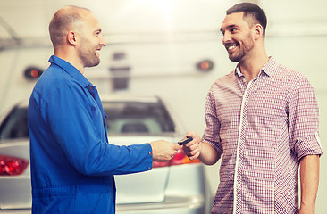 Image showing auto mechanic giving key to man at car shop