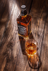 Image showing UKRAINE, KYIV-MARCH 11, 2015. Bottle of Jack Daniel\'s Tennessee whiskey with glass of drink on a wooden table.