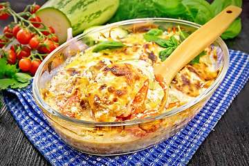 Image showing Zucchini baked with tomatoes in glass pan on dark board