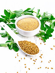Image showing Fenugreek in spoon and bowl with leaves on white wooden board