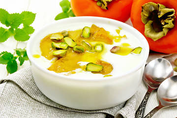 Image showing Dessert of yogurt and persimmon in bowl on wooden board