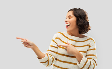 Image showing happy smiling woman pointing fingers to something