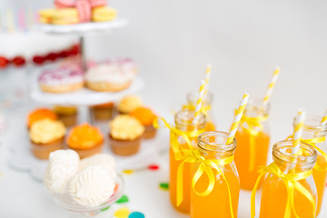 Image showing orange juice in glass bottles with paper straws