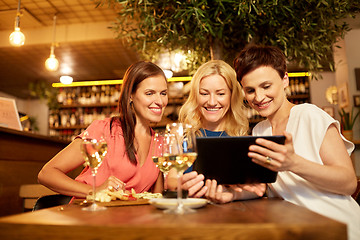 Image showing women with tablet pc at wine bar or restaurant