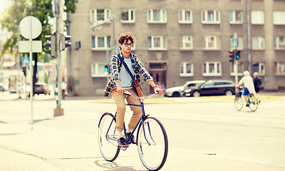 Image showing young hipster man with bag riding fixed gear bike