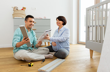 Image showing family couple with user manual assembling baby bed