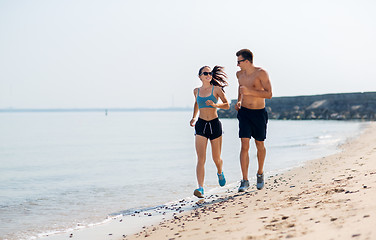 Image showing couple in sports clothes running along on beach