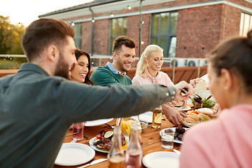 Image showing friends eating burgers at dinner party on rooftop