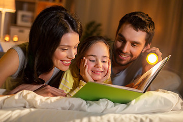 Image showing happy family reading book in bed at night at home