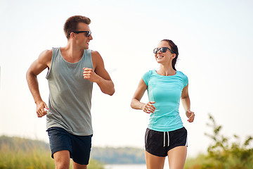 Image showing couple in sports clothes running along on beach