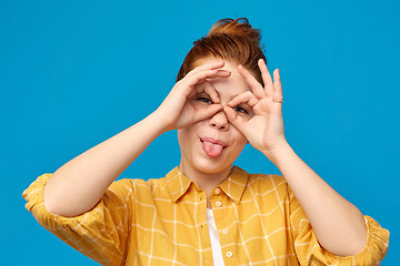 Image showing red haired teenage girl making finger glasses