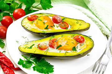 Image showing Scrambled eggs with tomatoes in avocado on wooden board