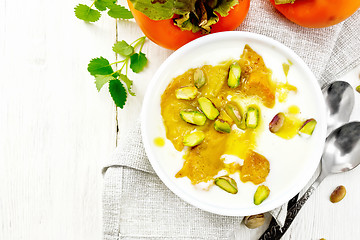 Image showing Dessert of yogurt and persimmon in bowl on light board top