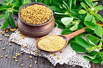 Image showing Fenugreek in spoon and bowl with green leaves on wooden board