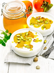 Image showing Dessert of yogurt and persimmon two bowls on wooden board