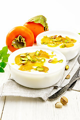 Image showing Dessert of yogurt and persimmon two bowls on board