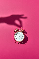 Image showing Hand\'s shadows holds retro golden painted alarmclock.