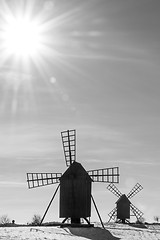 Image showing Sun and sunbeams by two old windmills