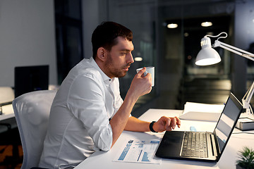 Image showing businessman with coffee and laptop at night office