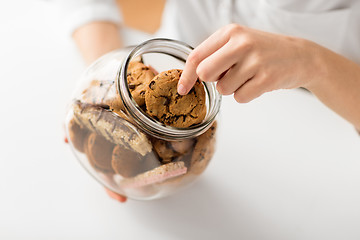 Image showing close up of woman taking oatmeal cookies from jar