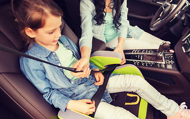 Image showing happy woman fastening child with seat belt in car