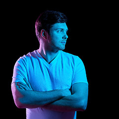 Image showing man with crossed arms over neon lights in darkness