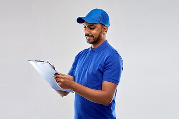 Image showing happy indian delivery man with clipboard in blue