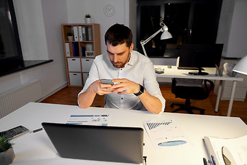 Image showing businessman with smartphone and computer at office