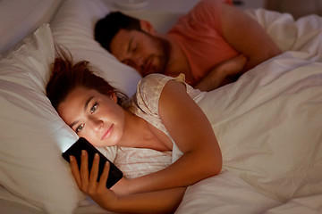 Image showing woman using smartphone while boyfriend is sleeping