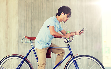 Image showing man with smartphone and earphones on bicycle