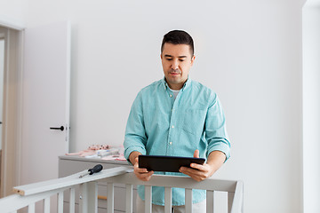 Image showing father with tablet pc assembling baby bed at home