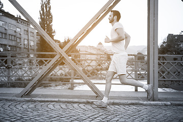 Image showing man jogging across the bridge at sunny morning